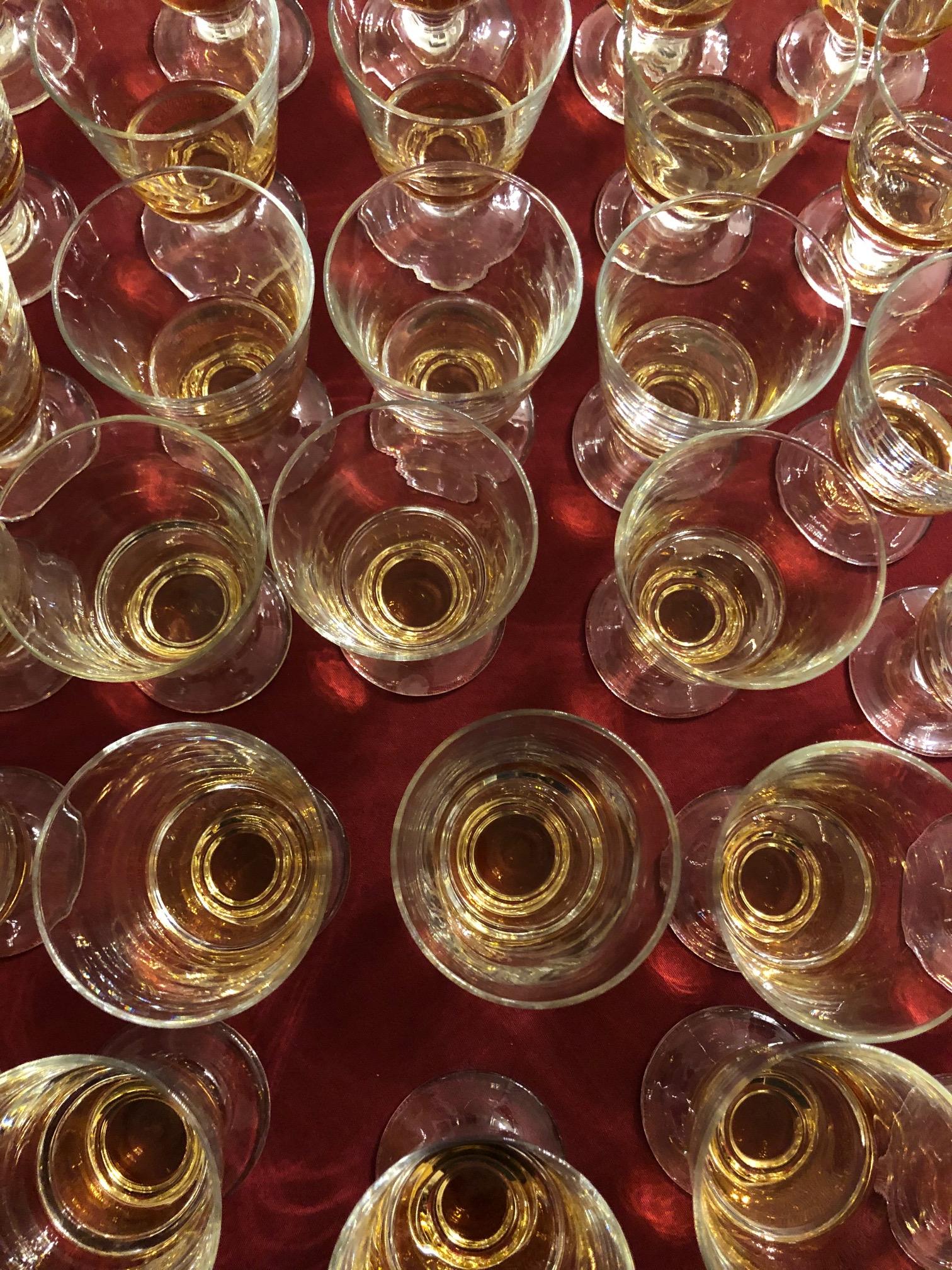 Overhead view of multiple glasses with whiskey pours.